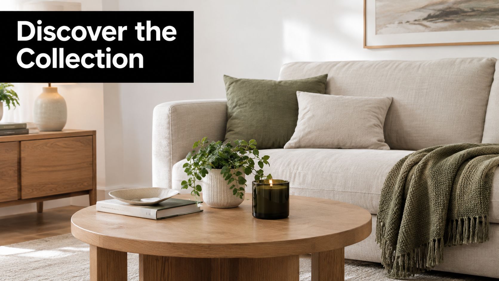 A modern living room with a neutral sofa, coffee table, green throw blanket, and decorative plant.