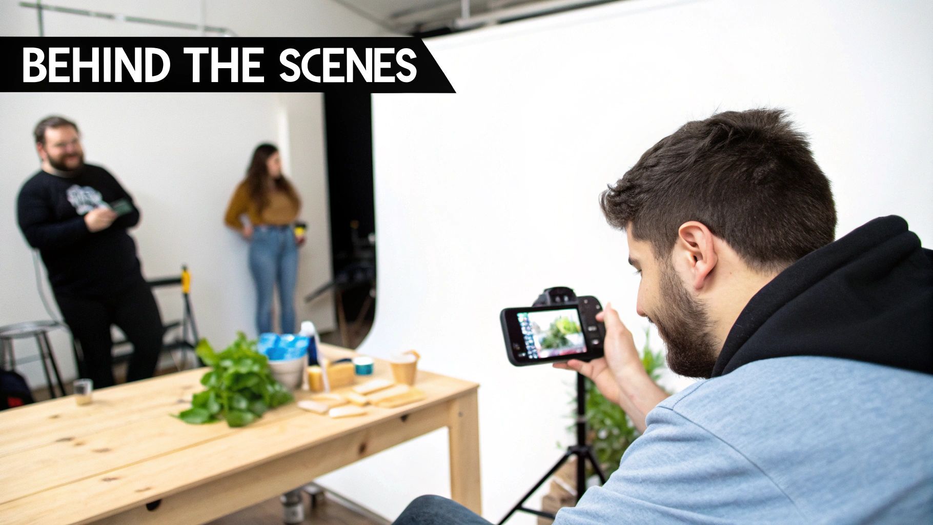 Un fotògraf repassa imatges en una càmera durant una sessió fotogràfica "behind the scenes" amb models i props.