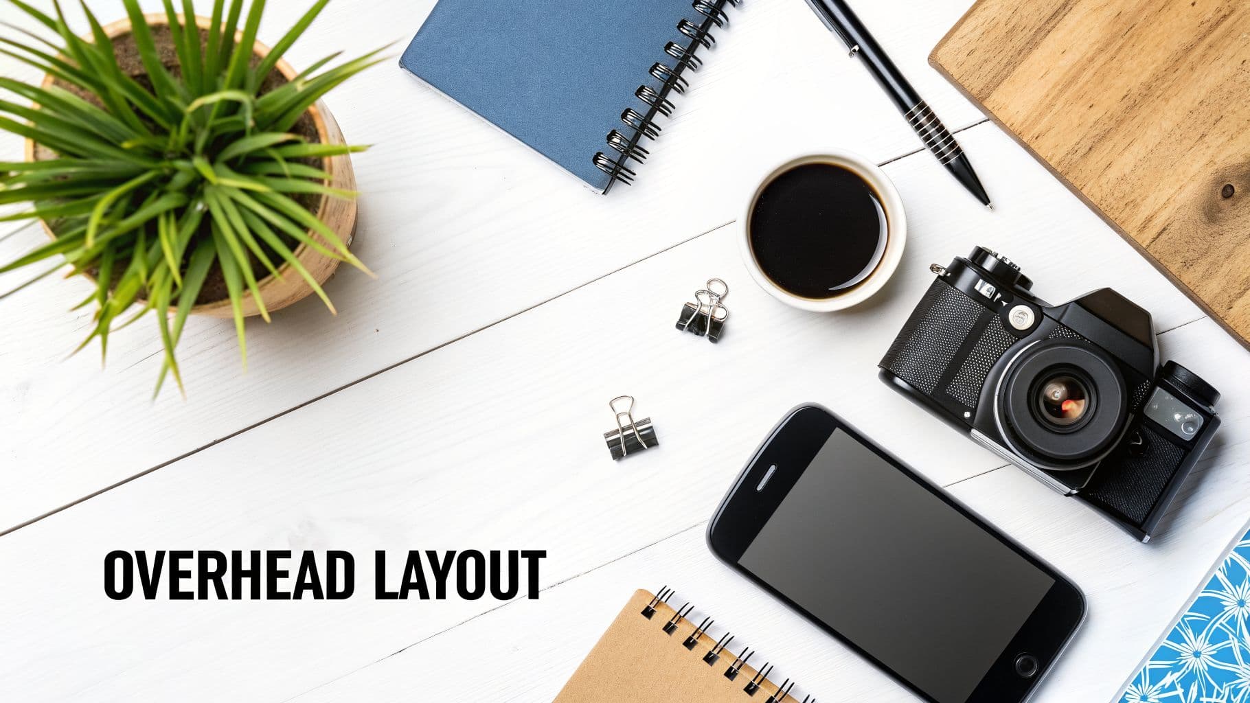 식물, 커피, 카메라, 스마트폰, 노트북이 있는 깨끗한 흰색 나무 책상 오버헤드 샷.